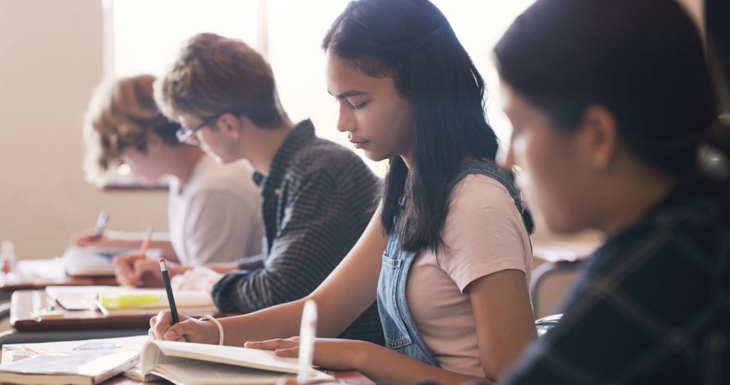 Shot of teenagers writing an exam in a classroom